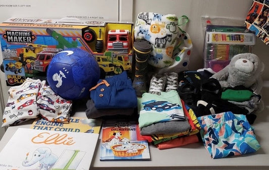 A shelf display of toys, socks, art supplies, a stuffed animal, and folded children's clothing at a boutique shop.